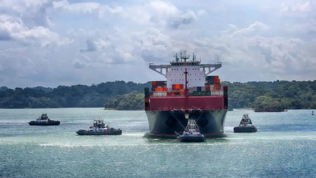 Photo caption: tugboats and a container ship near the Panama Canal. Photo credit: Panama Canal Authority